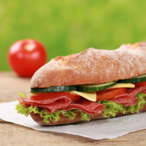 Baguette with salami, cheese and lettuce, garnished with a tomato